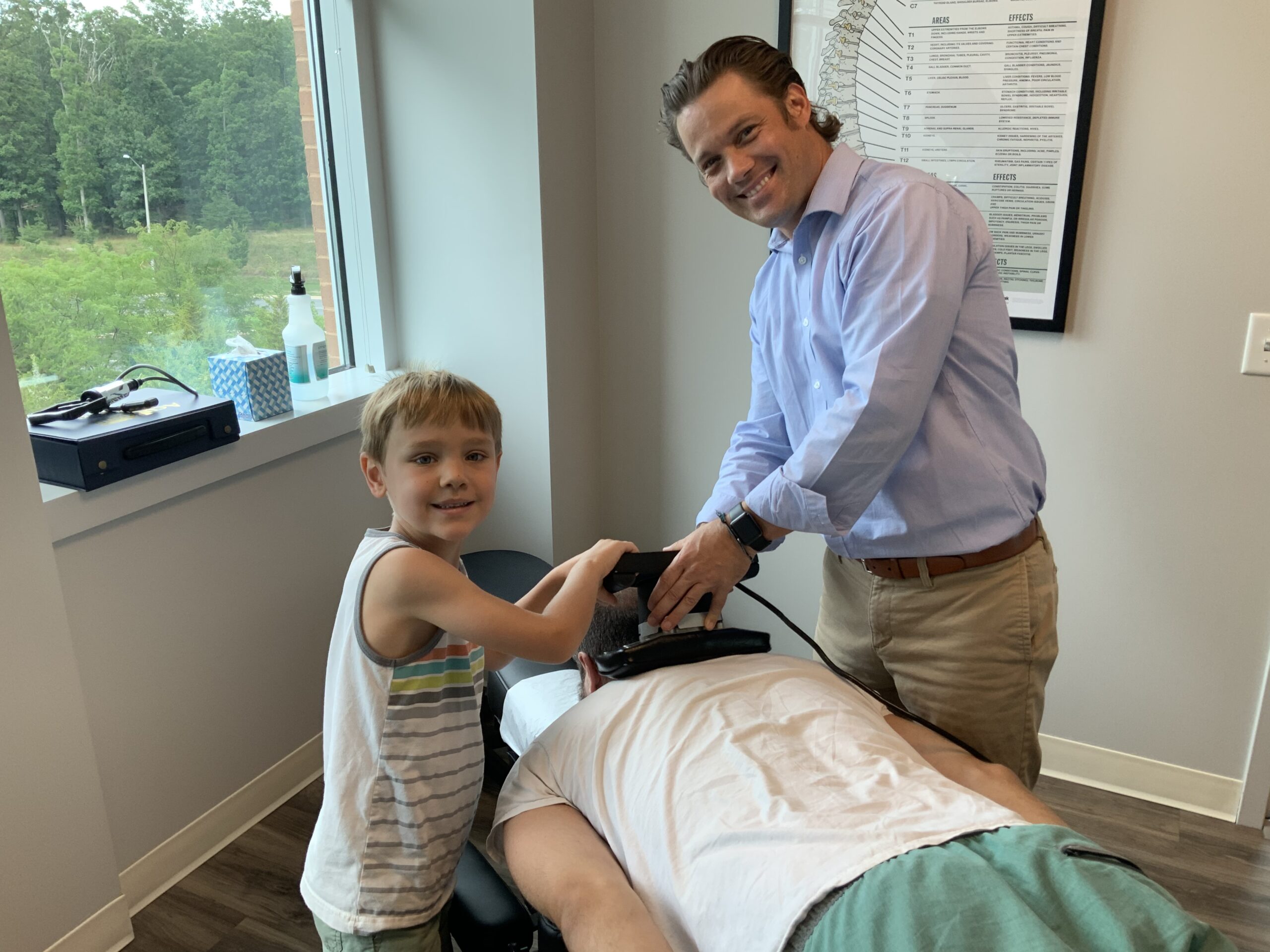 Dr. Keith Brassfield, DC, together with his son is performing a treatment to the back of the patient - Chiropractor Leesburg VA