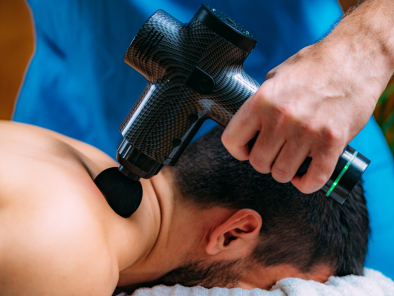 Dr. Keith Brassfield, DC is performing a treatment to a woman patient's shoulders - Chiropractor Leesburg VA